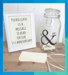 there is a glass jar with a sign on it next to a card and a small white frame