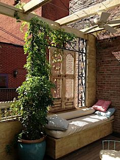 an outdoor seating area with potted plants on the side and brick wall behind it