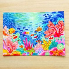 a colorful painting on a wooden surface with fish and corals in the water behind it