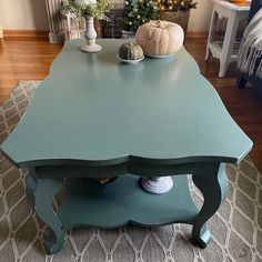 a blue table with two white pumpkins on it and a christmas tree in the background