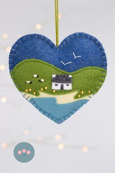 a heart shaped ornament hanging from a string with a house in the background