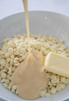 a white bowl filled with beans and cheese being poured into the dressing mixture to make peanut butter