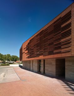 the exterior of a building with brick walkways and large wooden slats on it