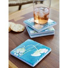 four coasters with flowers on them are sitting on a table next to crackers