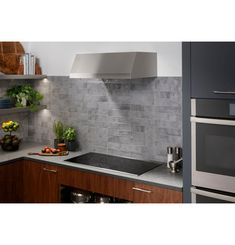 a modern kitchen with stainless steel appliances and gray tile backsplash, along with wooden cabinets