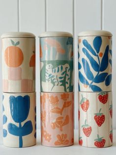 four different types of ceramic containers on a white surface with blue, orange and pink designs