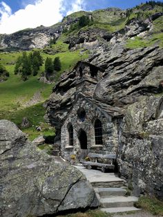 an old stone church built into the side of a rocky mountain with stairs leading up to it