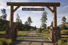 the entrance to rose valley ranch is shown in this image, it's surrounded by tall grass and trees