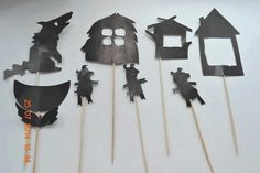 a group of cut out pieces of paper with bats and houses on sticks in front of them