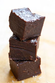 three pieces of brownie stacked on top of each other with sea salt around them