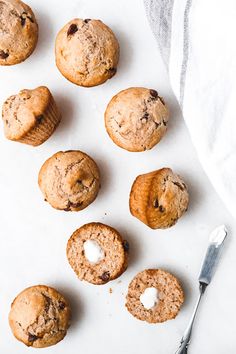 chocolate chip muffins with marshmallows on a white surface next to a spoon