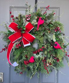 a christmas wreath with red birds and evergreens on it is hung on the front door