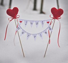 two heart shaped cake toppers on sticks in the snow