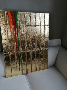 a white couch sitting next to a wall covered in gold foil and red, green and orange ribbons