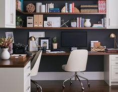 a desk with a computer and some books on it in front of a book shelf