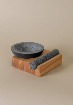 a stone bowl and a wooden stand with a black object on it's side