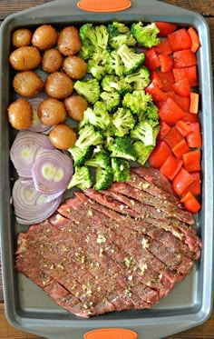 a tray filled with meat, vegetables and potatoes