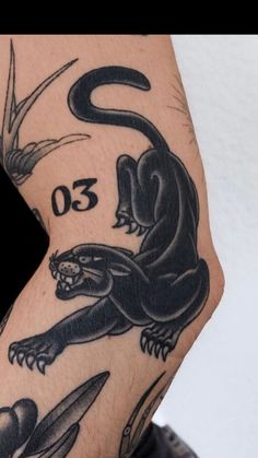 a man's arm with tattoos on it and an image of a black lizard