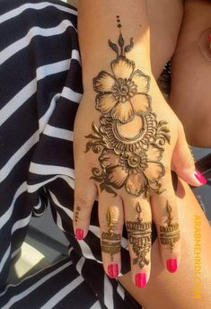 a woman's hand with hennap and flowers on her left hand, showing the