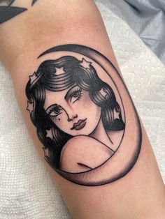 a woman's face in the shape of a crescent with stars on her arm