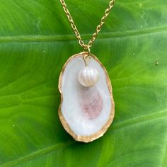 a shell with a pearl in it on a gold chain