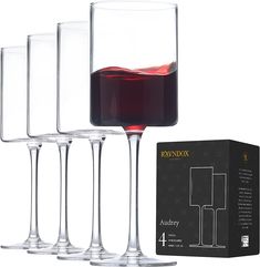 four wine goblets with red wine in them and a black box on the side