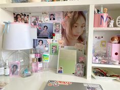 a white desk topped with lots of clutter next to a wall covered in pictures