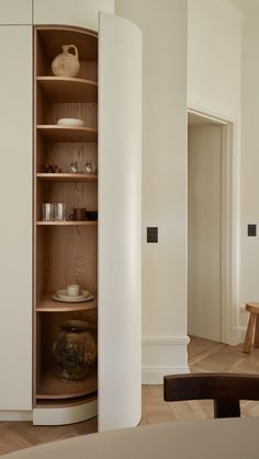 an empty room with white walls and wooden shelves in the corner next to a table