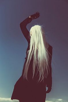 a woman with long white hair holding a bottle