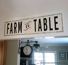 a sign that says farm to table hanging from the ceiling above a kitchen counter with a clock on it