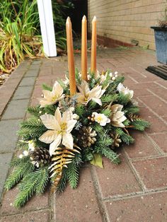 a christmas arrangement with candles and flowers on the ground