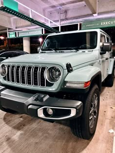 a jeep parked in a parking garage next to other cars and people looking at it