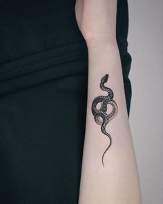 a woman's arm with a black snake tattoo on the left side of her arm