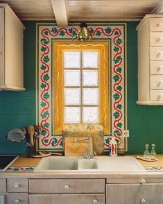 the kitchen is decorated in green and yellow with an intricately designed window above the sink