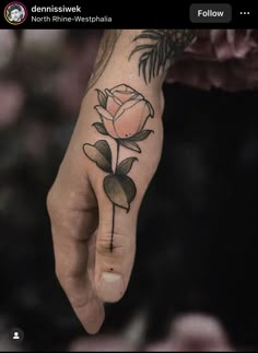 a person's hand with a rose tattoo on it