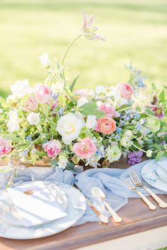 the table is set with plates, silverware and flowers