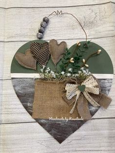 a heart hanging on the side of a wooden wall with flowers and burlocks