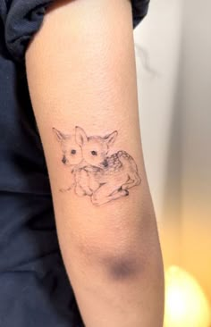 a woman's arm with a small tattoo of two kittens on the back of her arm