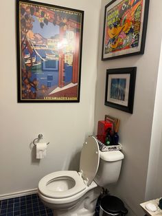 a bathroom with a toilet and pictures on the wall