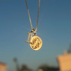 a gold necklace with an image of a lion on it and the word love is written in small letters