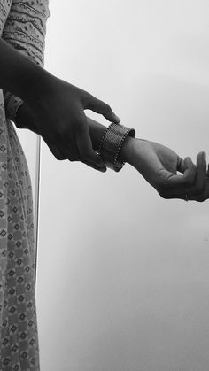 two people are holding hands with each other in black and white photo, one is holding the other's hand