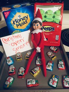 an elf is sitting on top of a cookie sheet with some candy bars in front of it