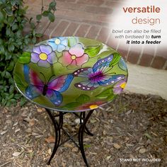 a glass bowl sitting on top of a metal stand next to a bush and brick wall