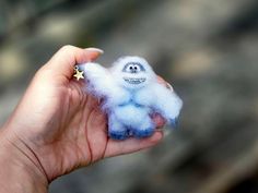 a hand holding a tiny blue and white stuffed animal with a star in it's ear