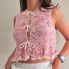 a woman wearing a pink crochet top and white shorts with her hands on her hips