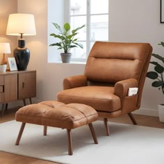 a chair and ottoman in a room with a potted plant on the side table