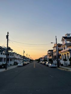 cars are parked on the street in front of row houses at sunset or sunrise time