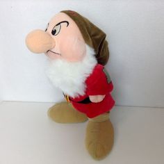 a stuffed toy with a red shirt and white beard is sitting on a table next to a wall