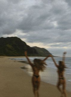 two women in bikinis are running on the beach