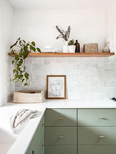 a kitchen with green cabinets and white tile backsplash, potted plants on the shelf